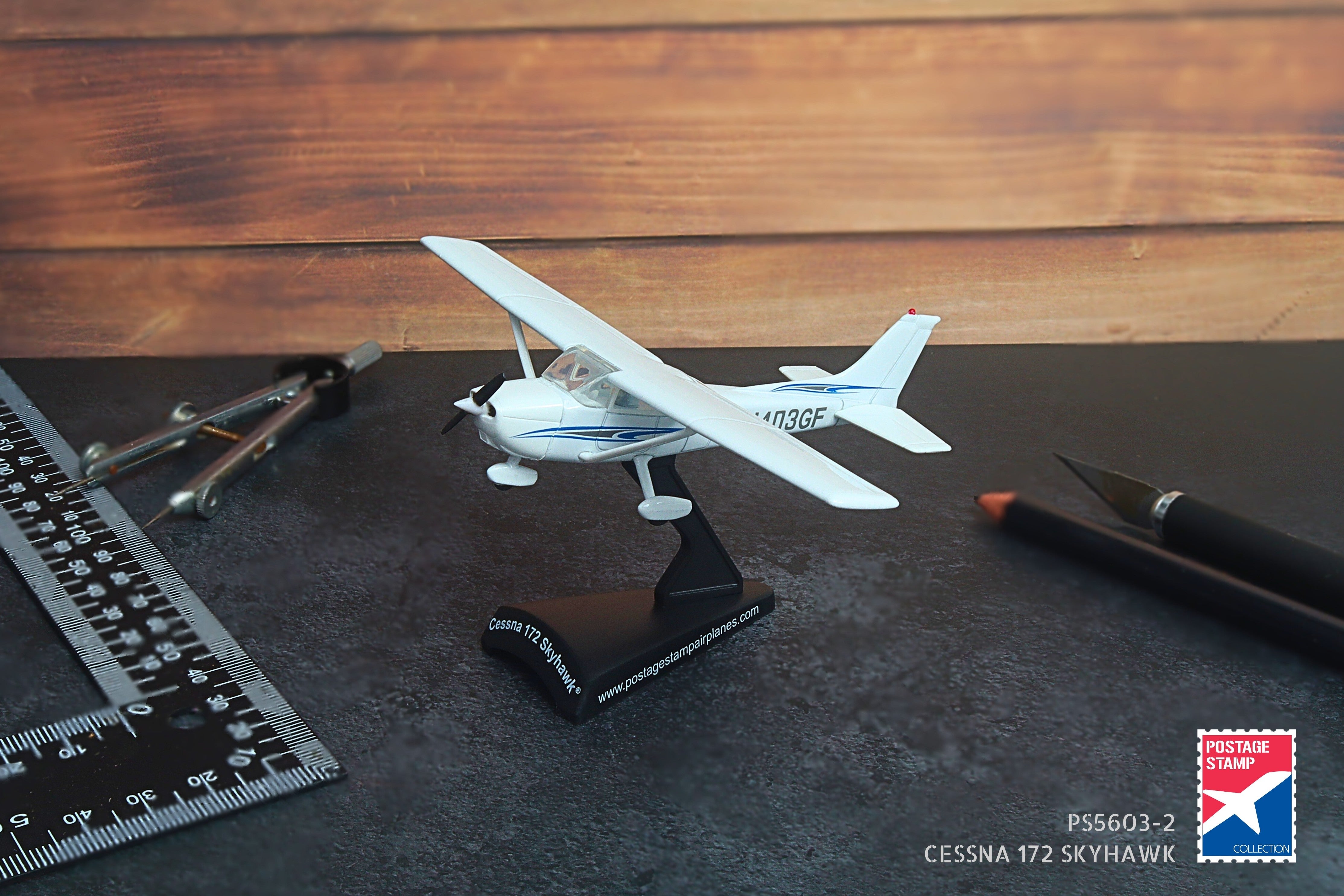 Model airplane on a stand with tools and a ruler on a wooden surface